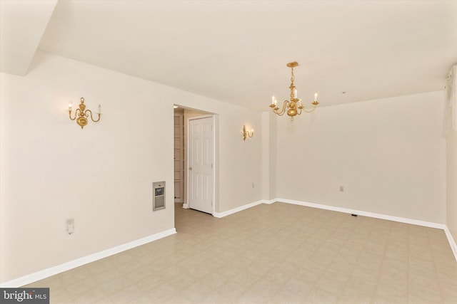 empty room with baseboards, an inviting chandelier, and light floors