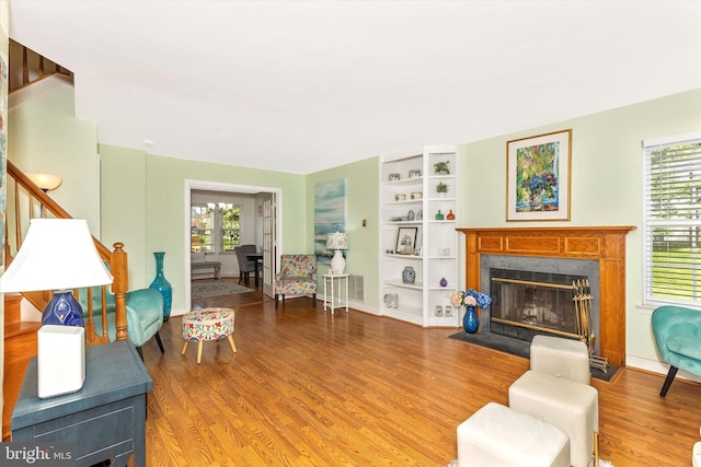 living room featuring stairs, a wealth of natural light, wood finished floors, and a high end fireplace