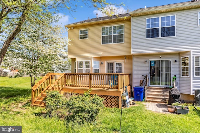 rear view of property featuring a lawn, a wooden deck, and entry steps