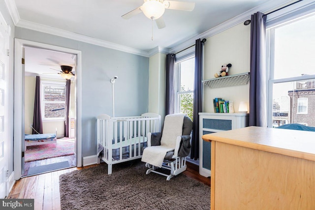 bedroom featuring crown molding, baseboards, ceiling fan, and wood finished floors