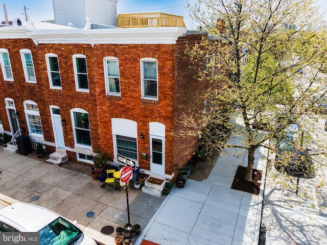 view of front of house with brick siding, central AC unit, a patio area, and entry steps