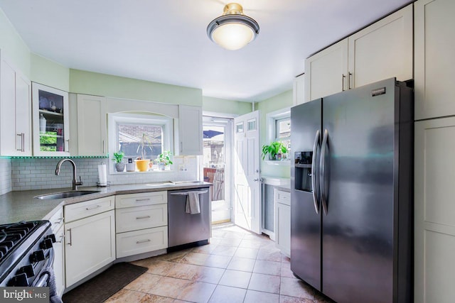 kitchen featuring white cabinetry, appliances with stainless steel finishes, a sink, and tasteful backsplash