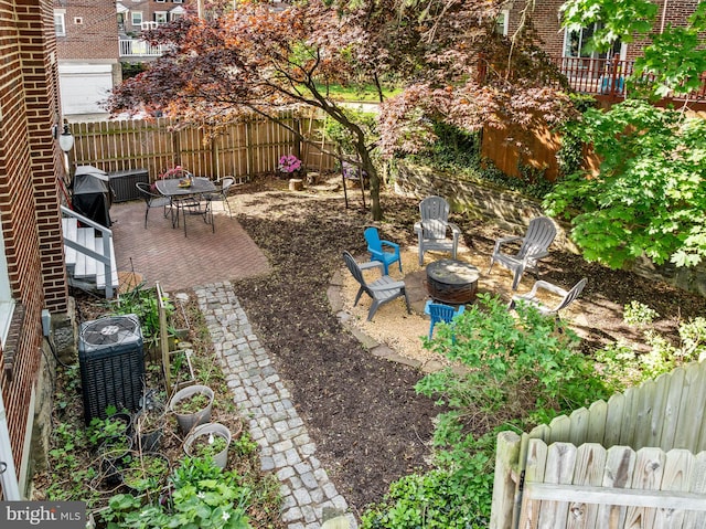 view of yard with a fenced backyard, a patio, central AC unit, and an outdoor fire pit