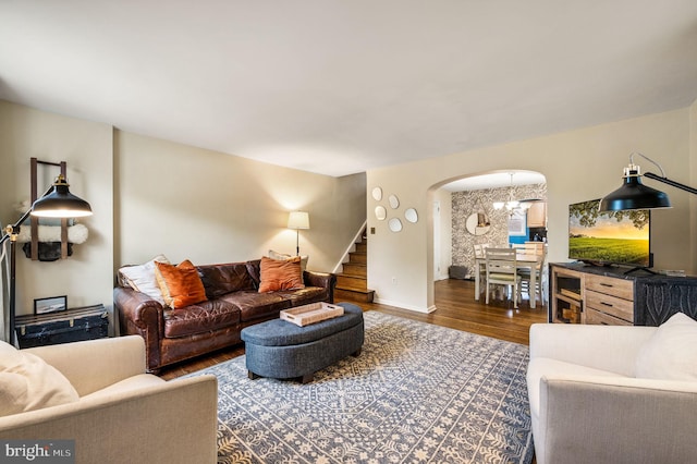 living area with stairway, arched walkways, and wood finished floors