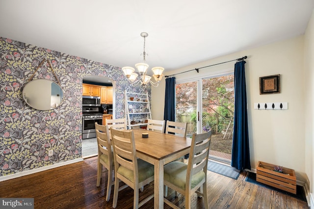 dining space featuring wallpapered walls, a notable chandelier, dark wood-style floors, and baseboards