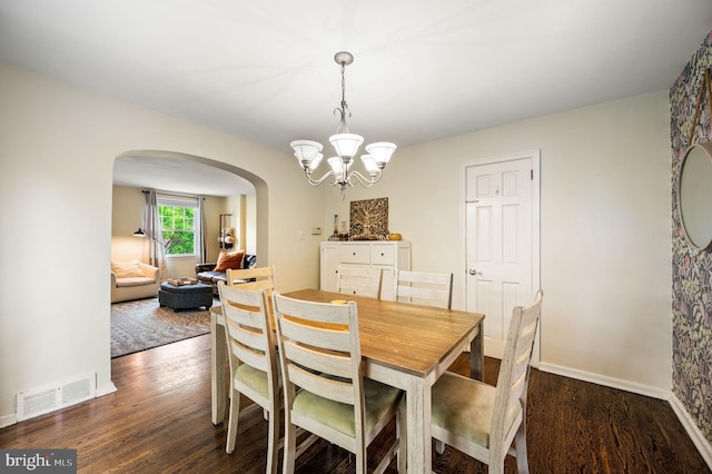 dining room featuring visible vents, arched walkways, wood finished floors, and a notable chandelier