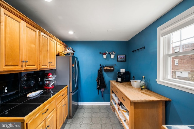 kitchen with tile counters, recessed lighting, baseboards, light floors, and stainless steel refrigerator with ice dispenser