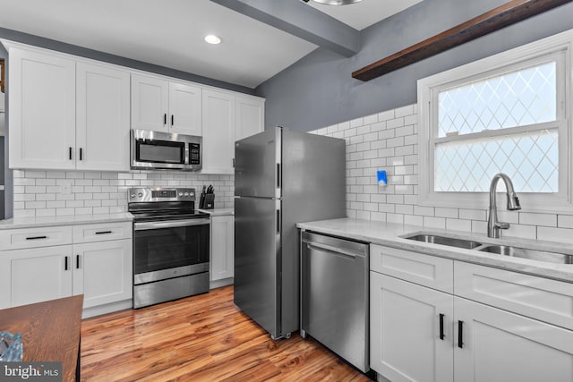 kitchen with a sink, white cabinetry, tasteful backsplash, and stainless steel appliances