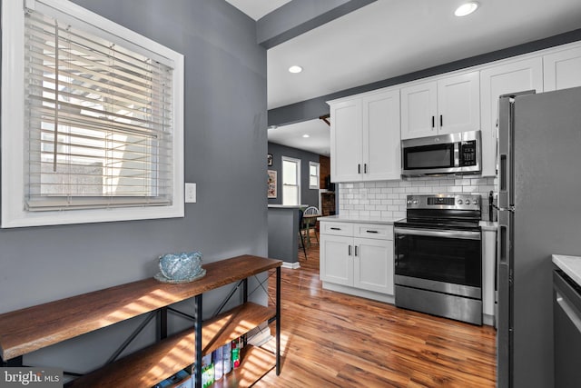 5310 Brabant Rd, Baltimore, MD 21229 - kitchen with appliances with stainless steel finishes, tasteful backsplash, white cabinetry, light wood-type flooring, and recessed lighting