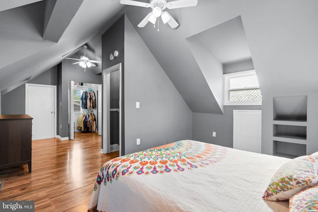 bedroom featuring wood finished floors, a ceiling fan, lofted ceiling, and a spacious closet