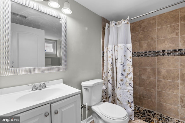 full bathroom featuring toilet, visible vents, tiled shower, and vanity
