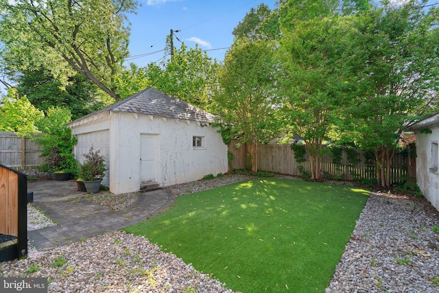 view of yard with a fenced backyard, an outbuilding, and a detached garage