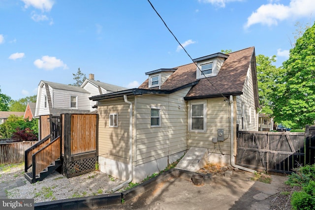 rear view of house featuring fence and a shingled roof