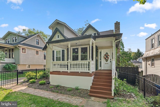 bungalow-style home with a porch, fence, and a chimney