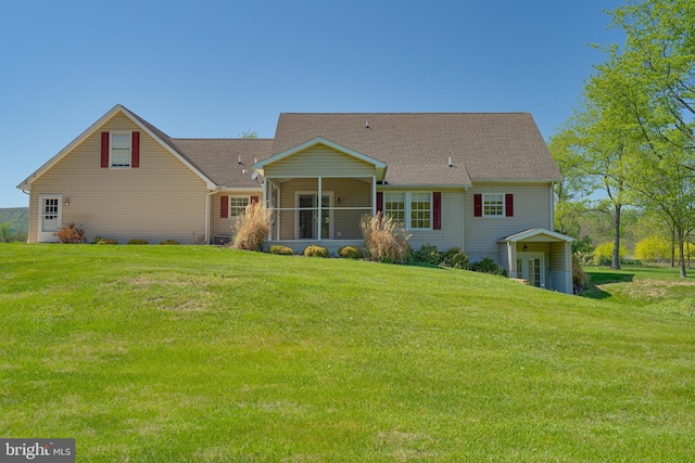 rear view of house featuring a lawn, roof with shingles, and a sunroom