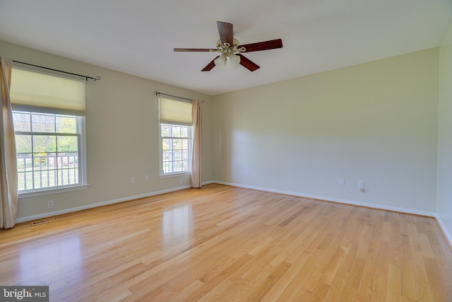 empty room featuring a ceiling fan, baseboards, visible vents, and light wood finished floors