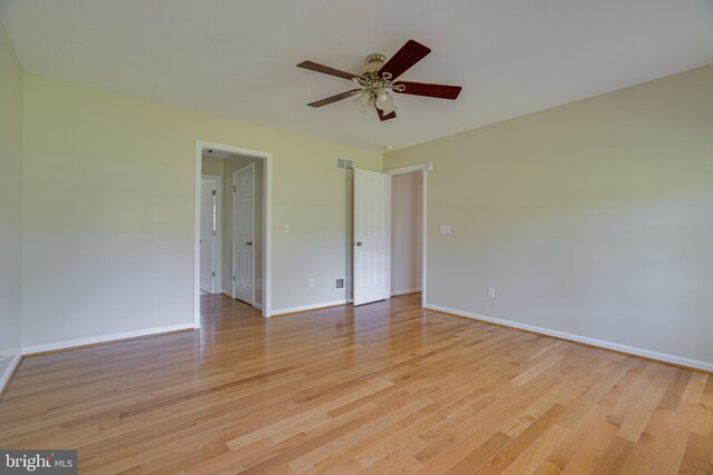 unfurnished room featuring light wood-style floors, baseboards, a ceiling fan, and visible vents