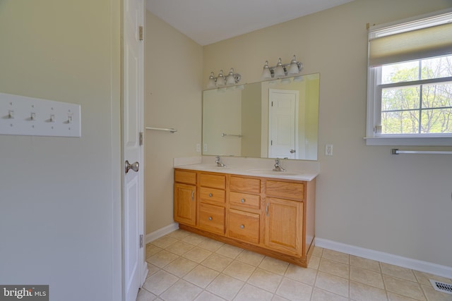 full bath featuring double vanity, a sink, baseboards, and tile patterned flooring