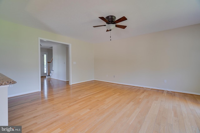 unfurnished room featuring baseboards, light wood finished floors, and ceiling fan