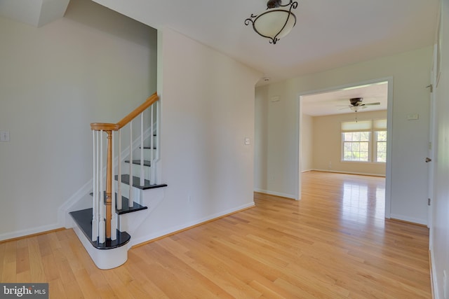 stairs featuring baseboards, ceiling fan, and wood finished floors