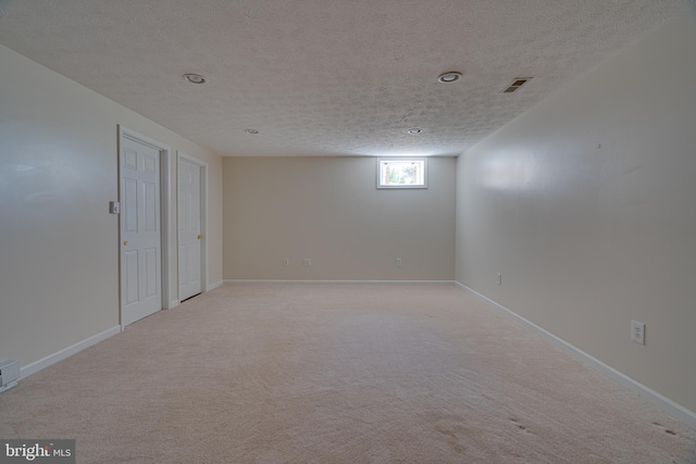 below grade area featuring a textured ceiling, light colored carpet, and baseboards