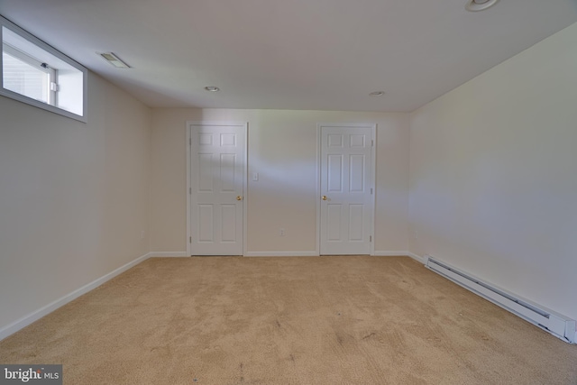spare room with baseboards, a baseboard radiator, visible vents, and light carpet
