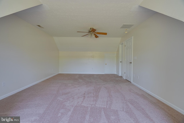 empty room featuring carpet flooring, a ceiling fan, baseboards, and vaulted ceiling