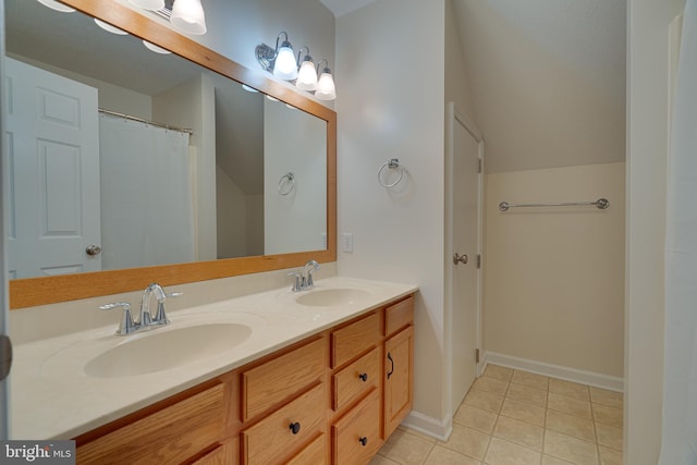 bathroom featuring double vanity, tile patterned floors, a sink, and lofted ceiling