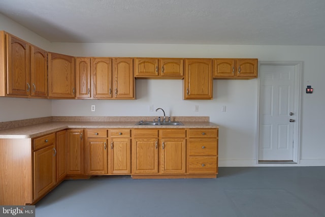 kitchen with a sink, light countertops, baseboards, and brown cabinets