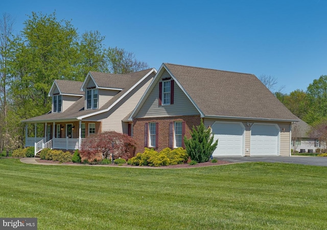 new england style home with a porch, an attached garage, driveway, and a front yard