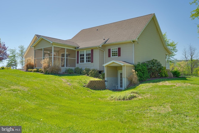 back of house featuring a sunroom, roof with shingles, and a yard