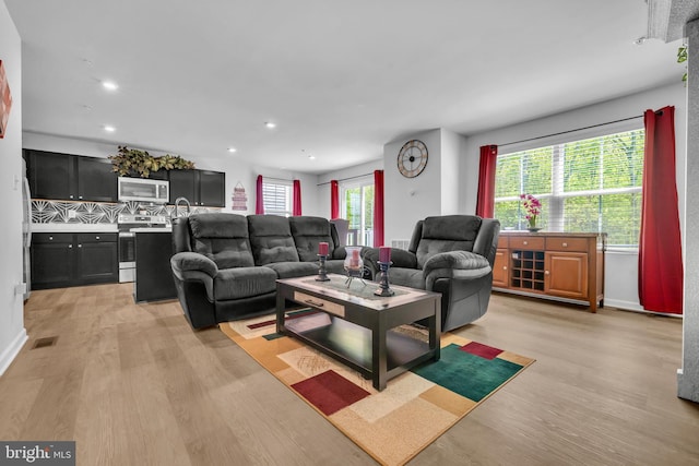 living room featuring recessed lighting, light wood-style flooring, and visible vents