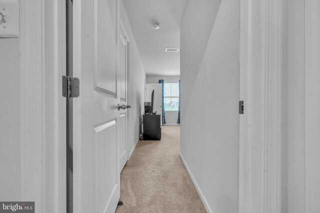 corridor featuring baseboards, visible vents, and light carpet