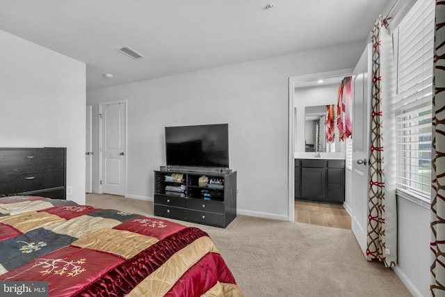 bedroom with carpet flooring, baseboards, visible vents, and connected bathroom