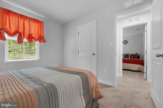 bedroom with baseboards, light colored carpet, and visible vents