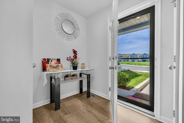 doorway to outside with baseboards, wood finished floors, and visible vents