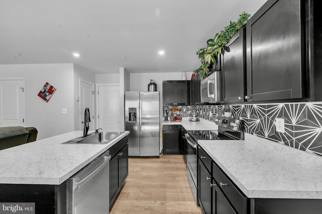 kitchen featuring light wood-style floors, light countertops, dark cabinets, a sink, and stainless steel appliances