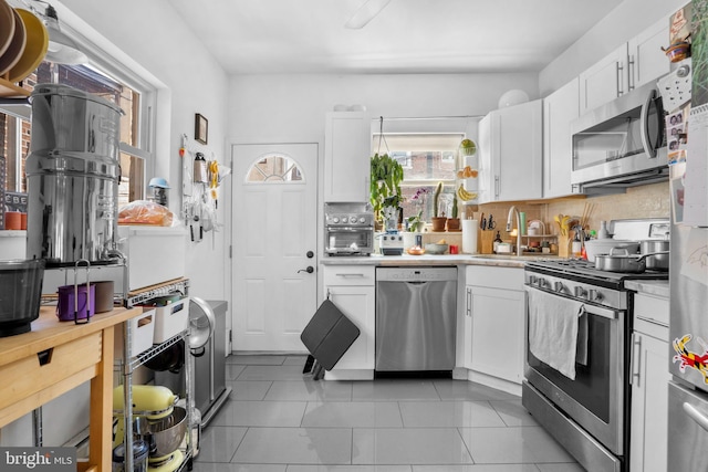 kitchen featuring a sink, appliances with stainless steel finishes, white cabinets, and a wealth of natural light