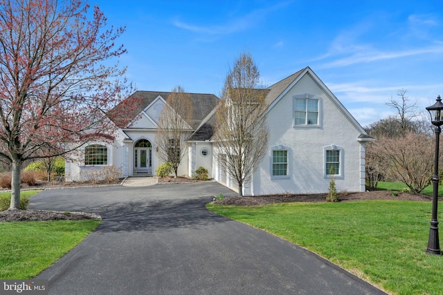 view of front of home with an attached garage, a front lawn, stucco siding, and driveway