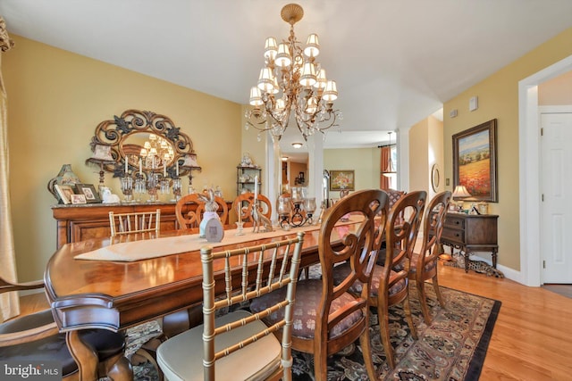 dining room with baseboards, a notable chandelier, and wood finished floors