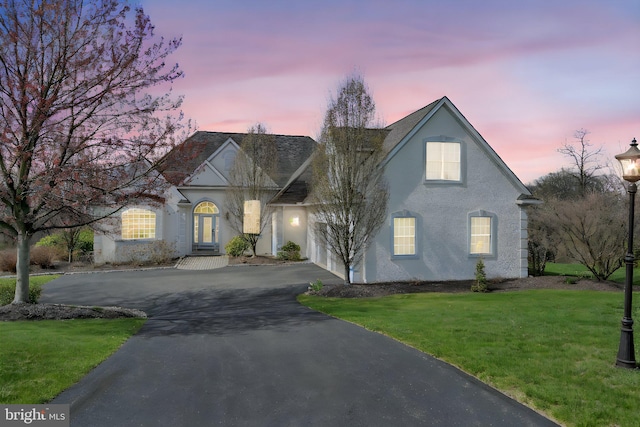 view of front of home with stucco siding, a front lawn, and aphalt driveway