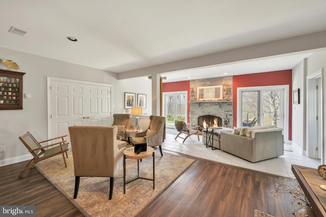 living room featuring visible vents, light wood-style flooring, a healthy amount of sunlight, and a fireplace
