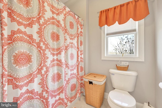 bathroom featuring a shower with shower curtain, toilet, baseboards, and tile patterned floors