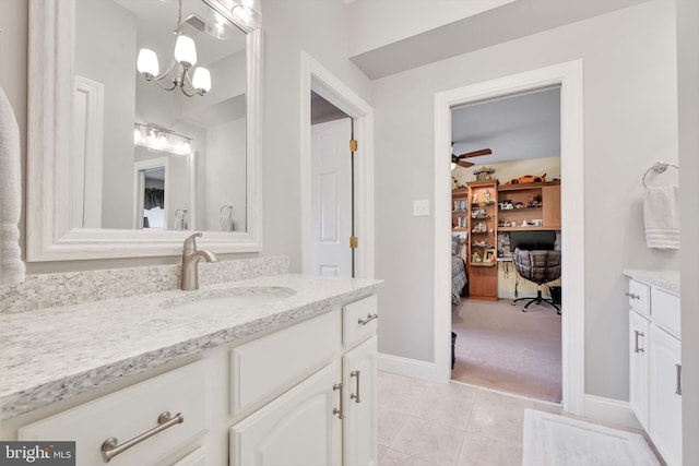 bathroom with baseboards, tile patterned flooring, ceiling fan with notable chandelier, and vanity