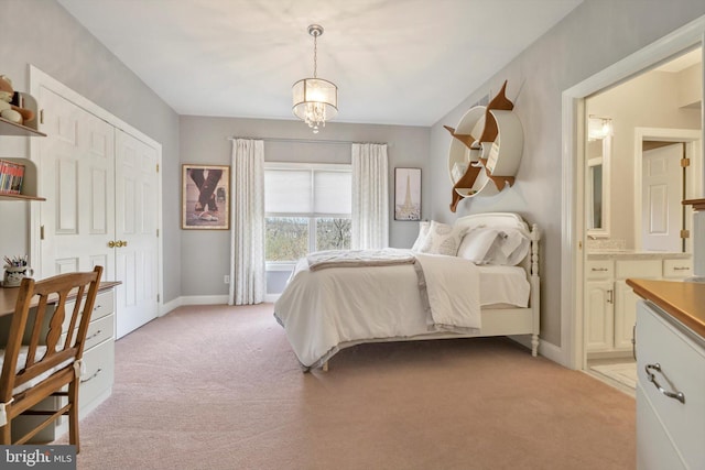 bedroom with light colored carpet, baseboards, ensuite bath, and a notable chandelier