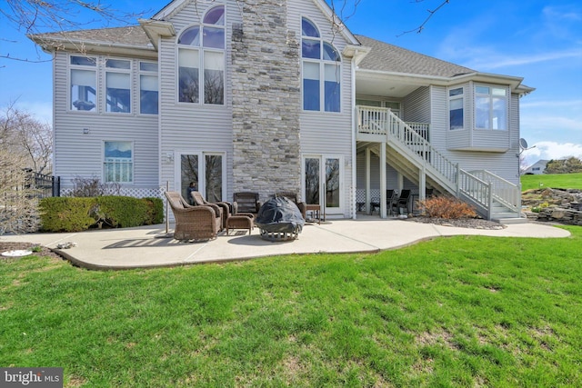 rear view of house with a lawn, stairs, and a patio