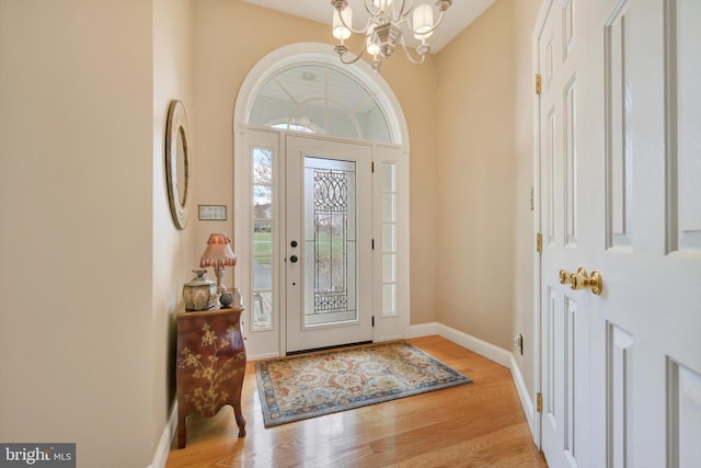 foyer entrance featuring light wood-style floors, baseboards, and a notable chandelier