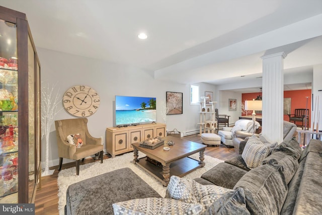 living area with baseboard heating, baseboards, decorative columns, and wood finished floors