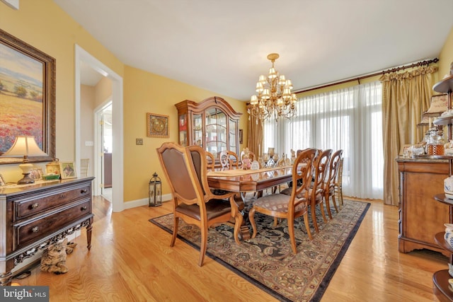 dining room featuring baseboards, a notable chandelier, and light wood-type flooring