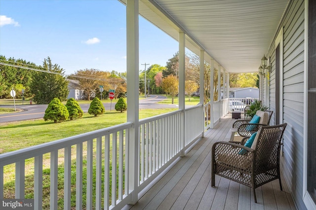wooden terrace featuring a lawn and a porch